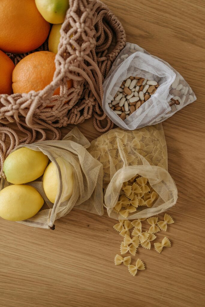 pexels-photo-7055090-7055090 Overhead view of eco-friendly mesh bags with oranges, lemons, beans, and pasta on a wooden surface.