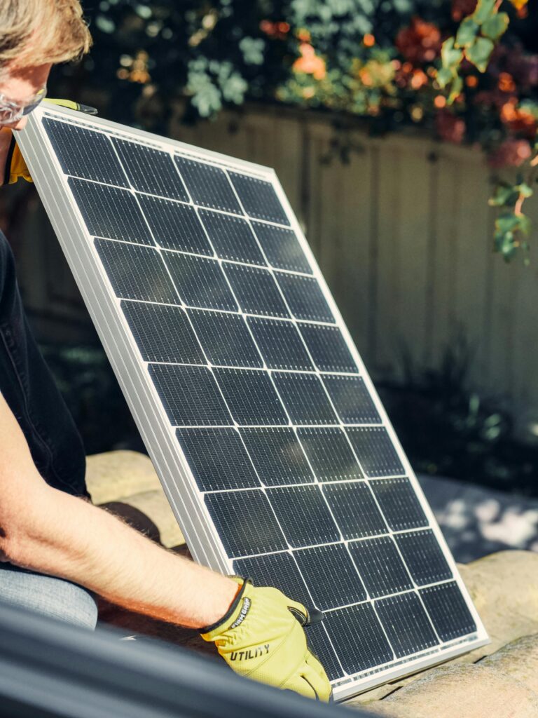 pexels-photo-9875410-9875410 A worker installs a solar panel in a garden, promoting clean energy.
