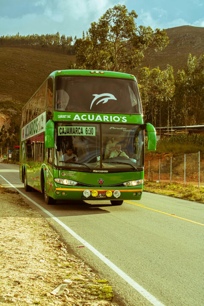 Green double-decker bus 'Acuario's' on a mountain road to Cajamarca, Peru.